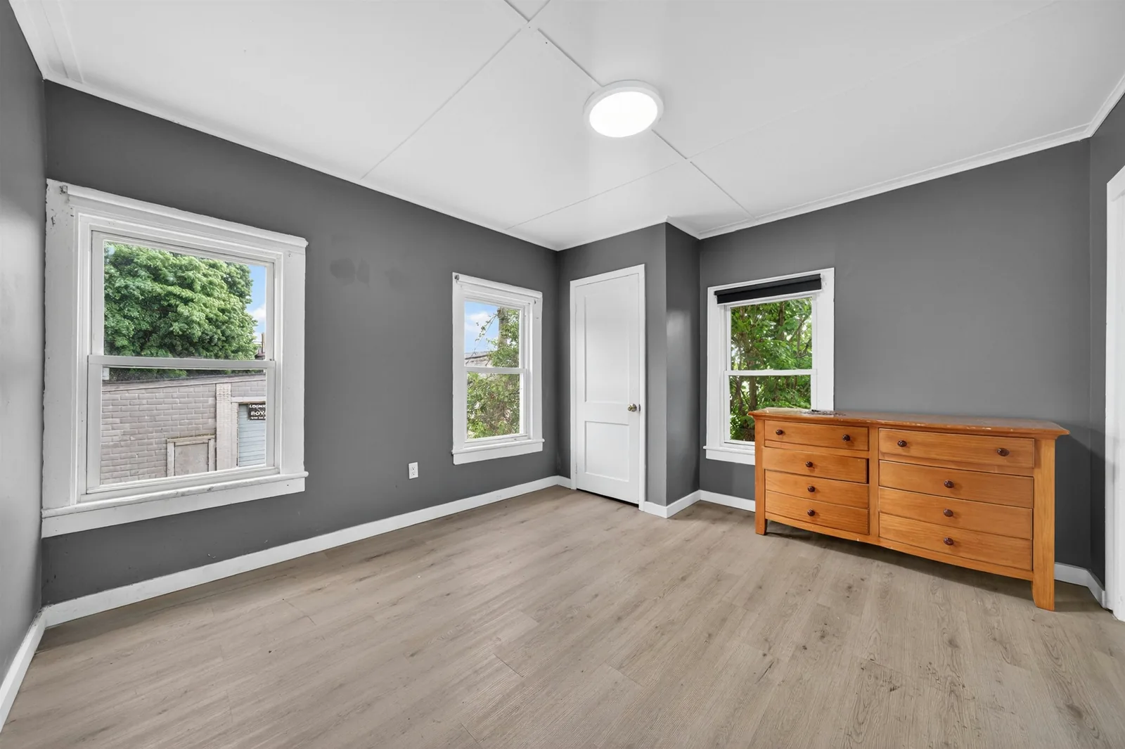 Bedroom with hardwood floors and three windows